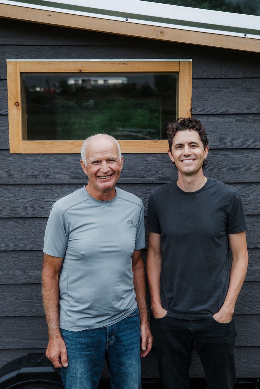 Stuart and his father standing side by side against the charcoal siding of the finished sauna