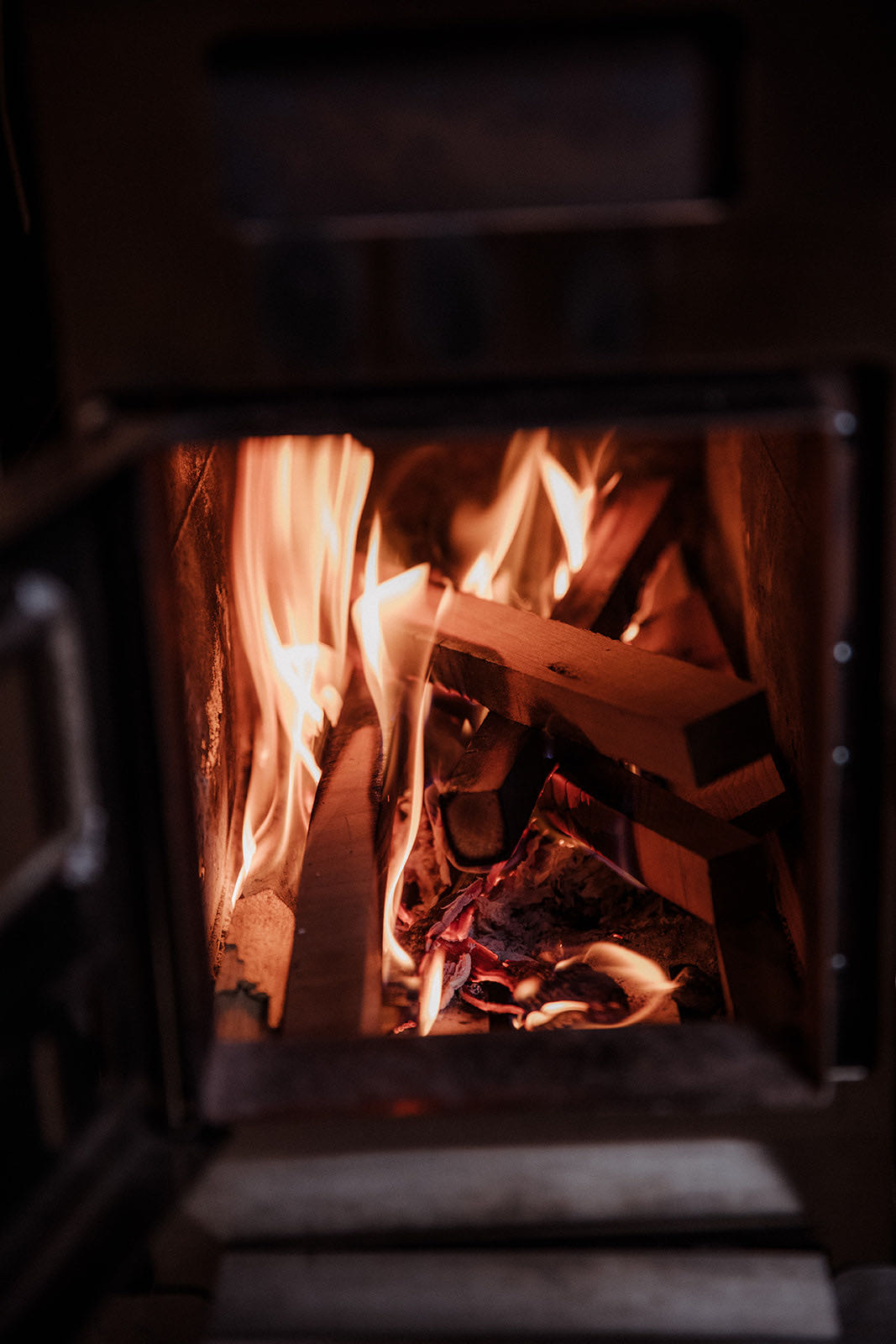 Split wood burning inside the open firebox of the sauna stove