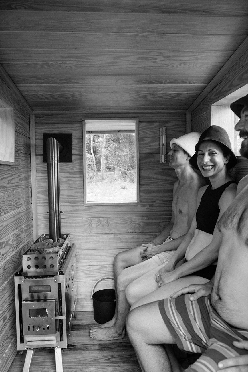 Friends in wool sauna hats laughing together on the bench between rounds