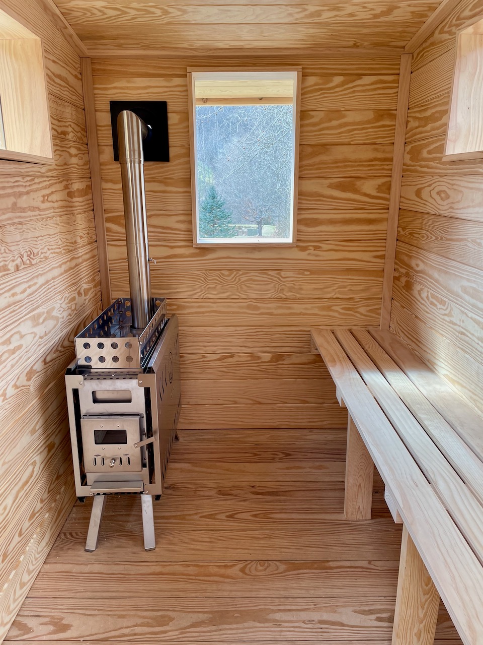 Warm pine interior of a Bushlot Sauna Club mobile sauna with wood-burning stove
